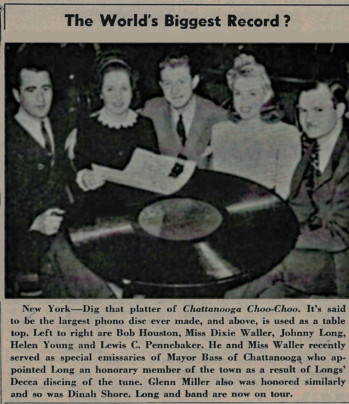 March 1942 Downbeat Magazine scan: Johnny Long posing with a giant novelty record prop on a table for a promotional photo op.